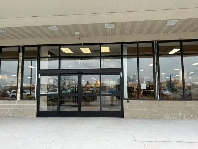 Retail aluminum storefront with a pair of glass entry doors under a canopy