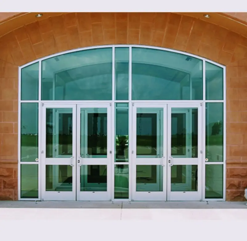 Aluminum storefront entrance with double doors and transom set inside a sandstone arch