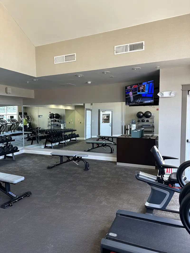 Mirror wall wrapping a fitness center with treadmills and weight benches