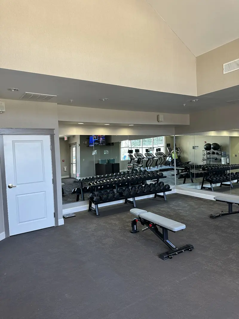 Full-height mirror wall installed in a fitness room with benches and dumbbells