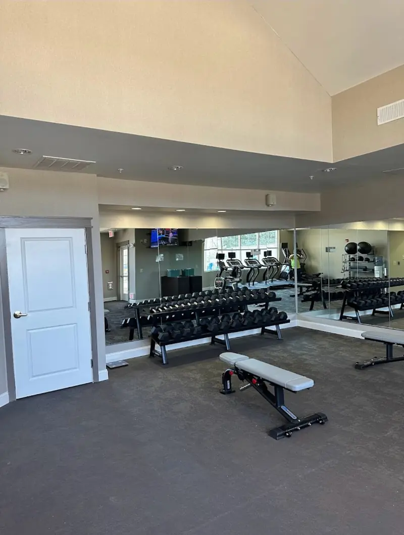 Mirrored wall behind a weight rack in a fitness room