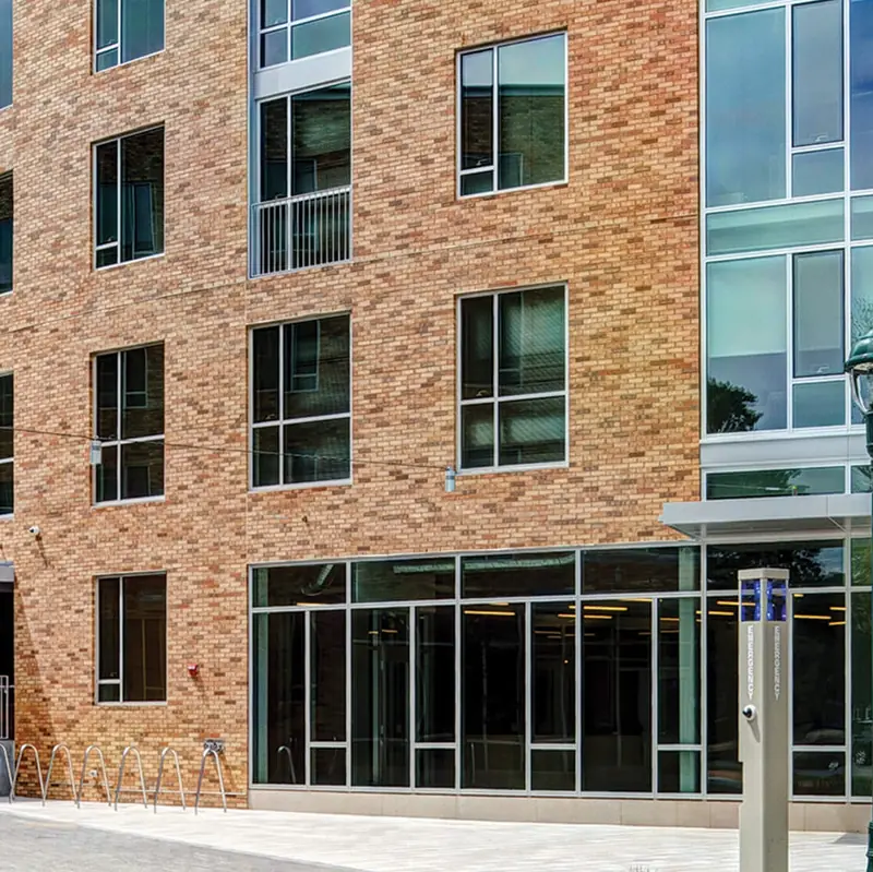 Brick mixed-use apartment building with a ground-floor aluminum storefront and a glass curtain wall corner