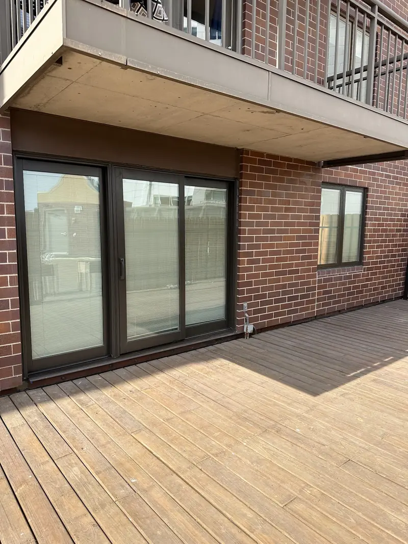 Dark-framed sliding patio doors on a brick apartment balcony