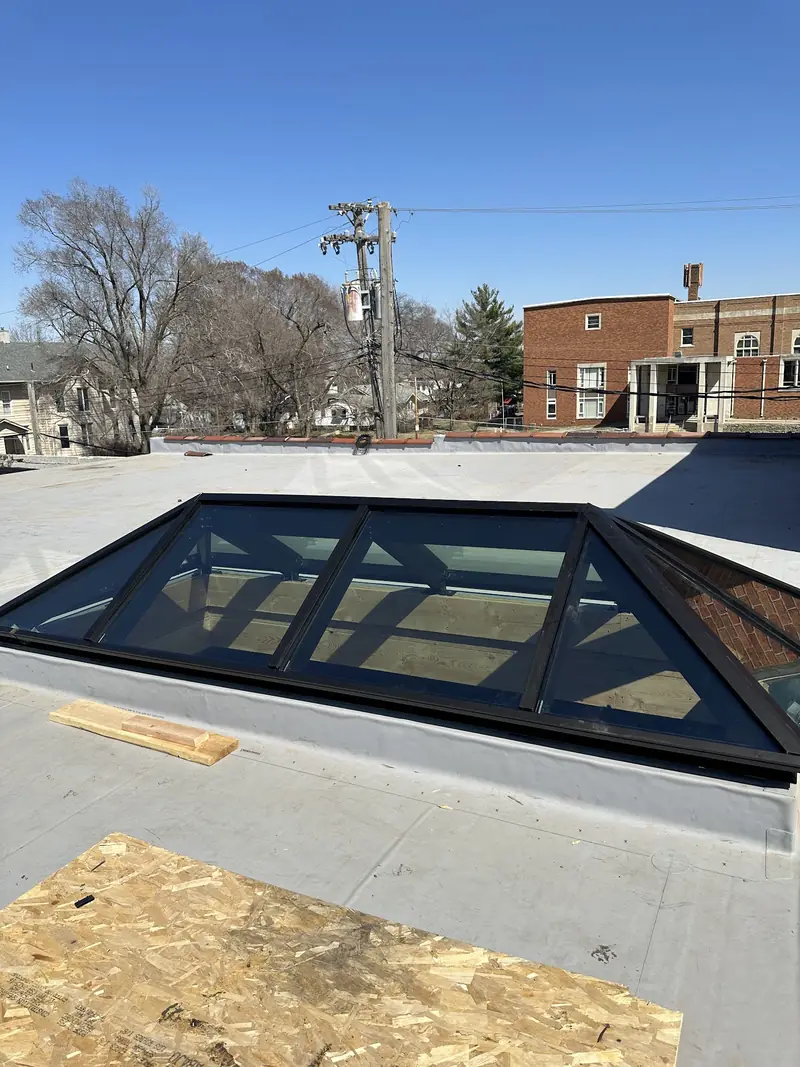 Pyramid skylight with dark aluminum frame installed on a flat commercial roof