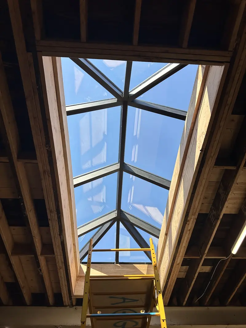 Hip skylight seen from below through open roof framing during installation