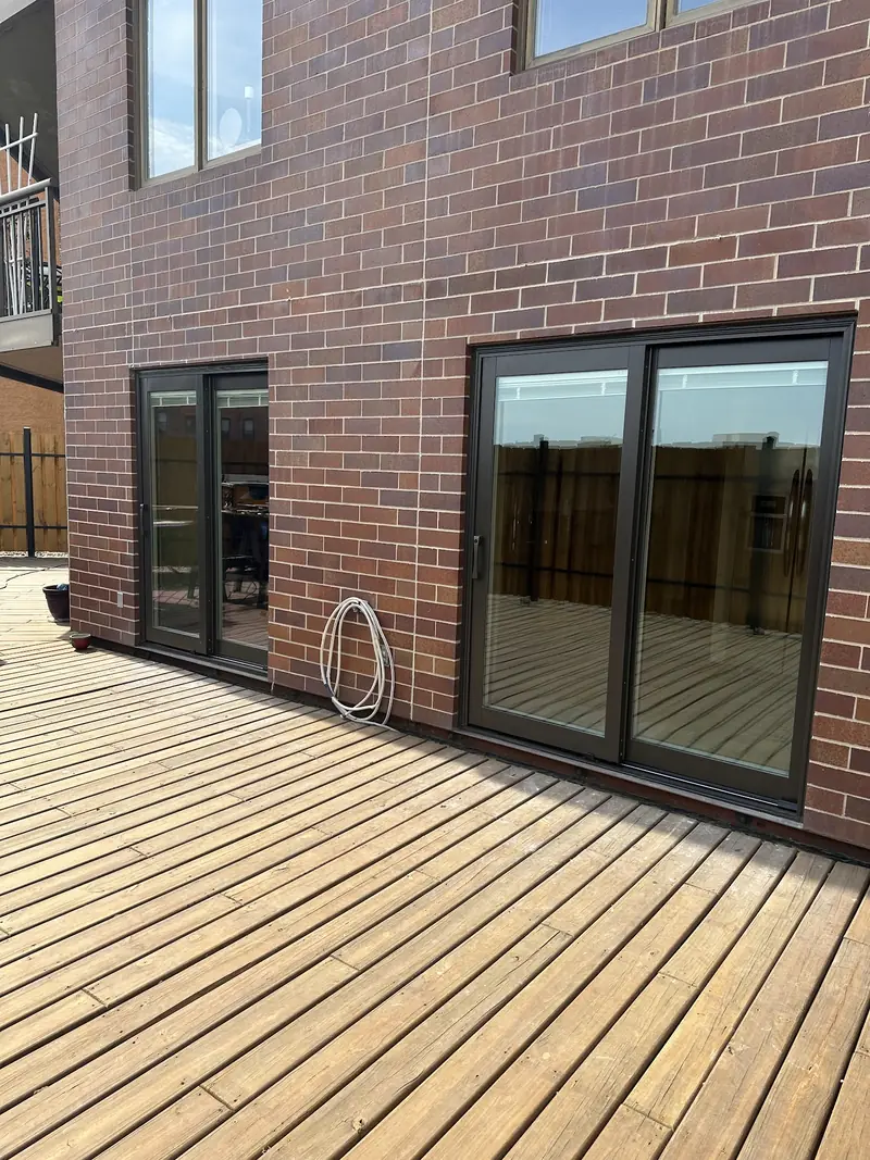 Sliding glass doors opening onto a wood deck on a brick building